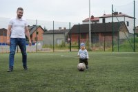 Roczny chłopczyk z piłką na boisku w asyście swojego taty
