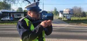 Na zdjęciu policjant ruchu drogowego stojący z ręcznym miernikiem prędkości